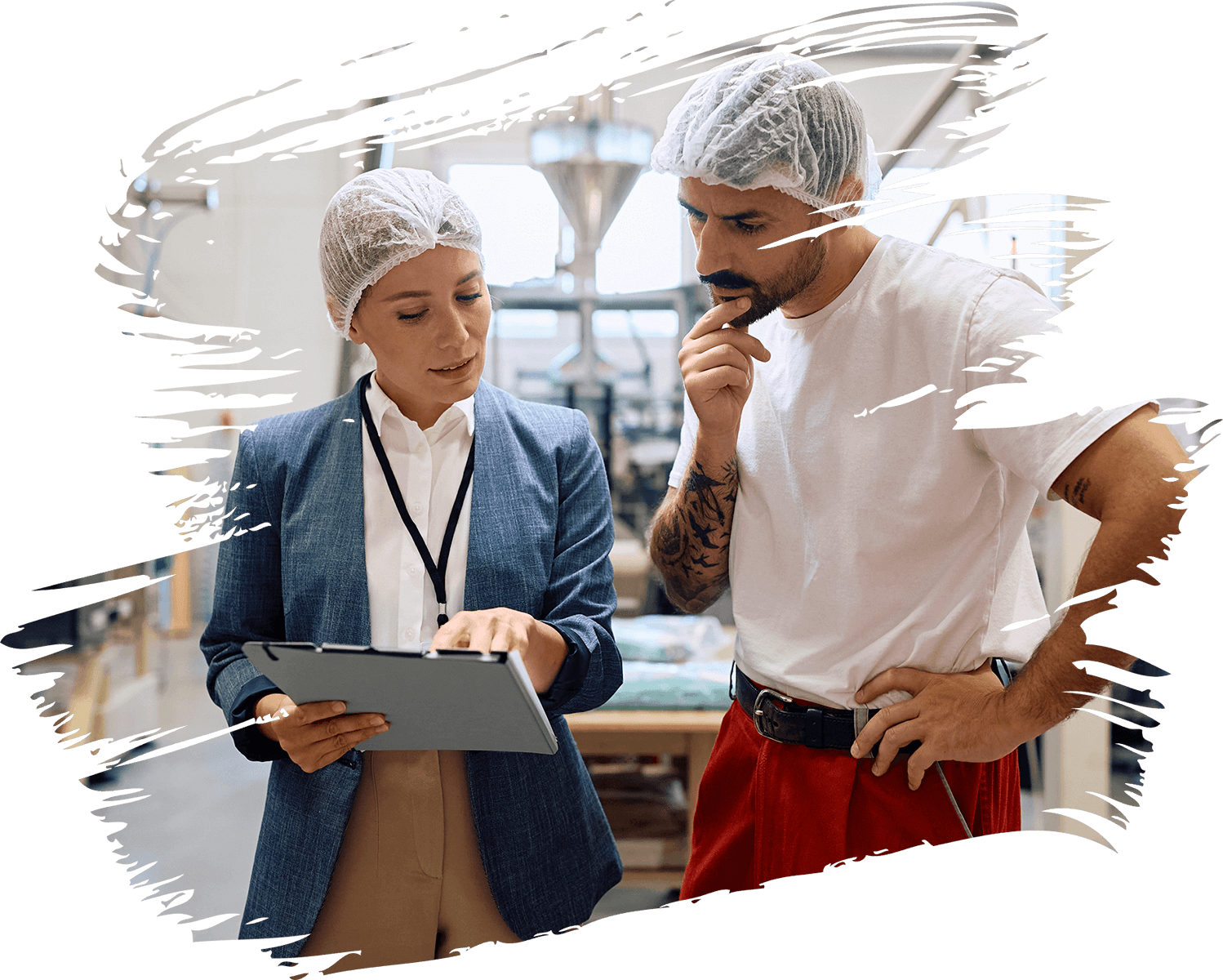 Two professionals in a factory discussing a tablet.