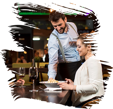 Waiter serving pasta to a woman in a restaurant setting